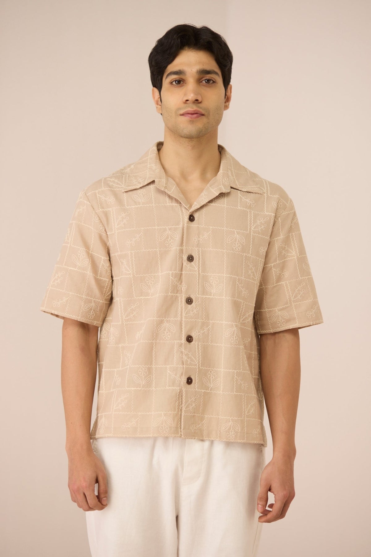 Man wearing a beige checkered shirt with short sleeves on a beige background Calling June