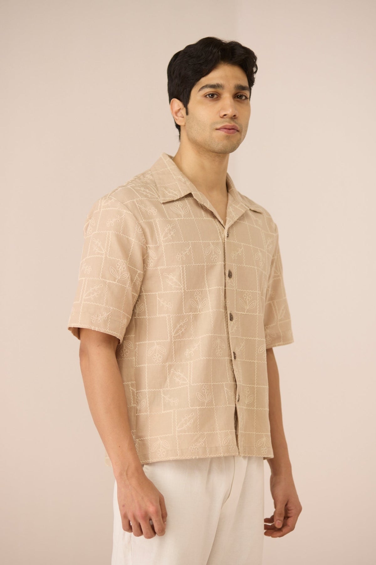 Man wearing a beige checkered shirt against a beige background Calling June