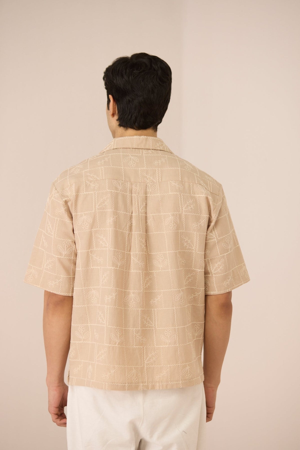 Man wearing a beige checkered shirt against a beige background Calling June