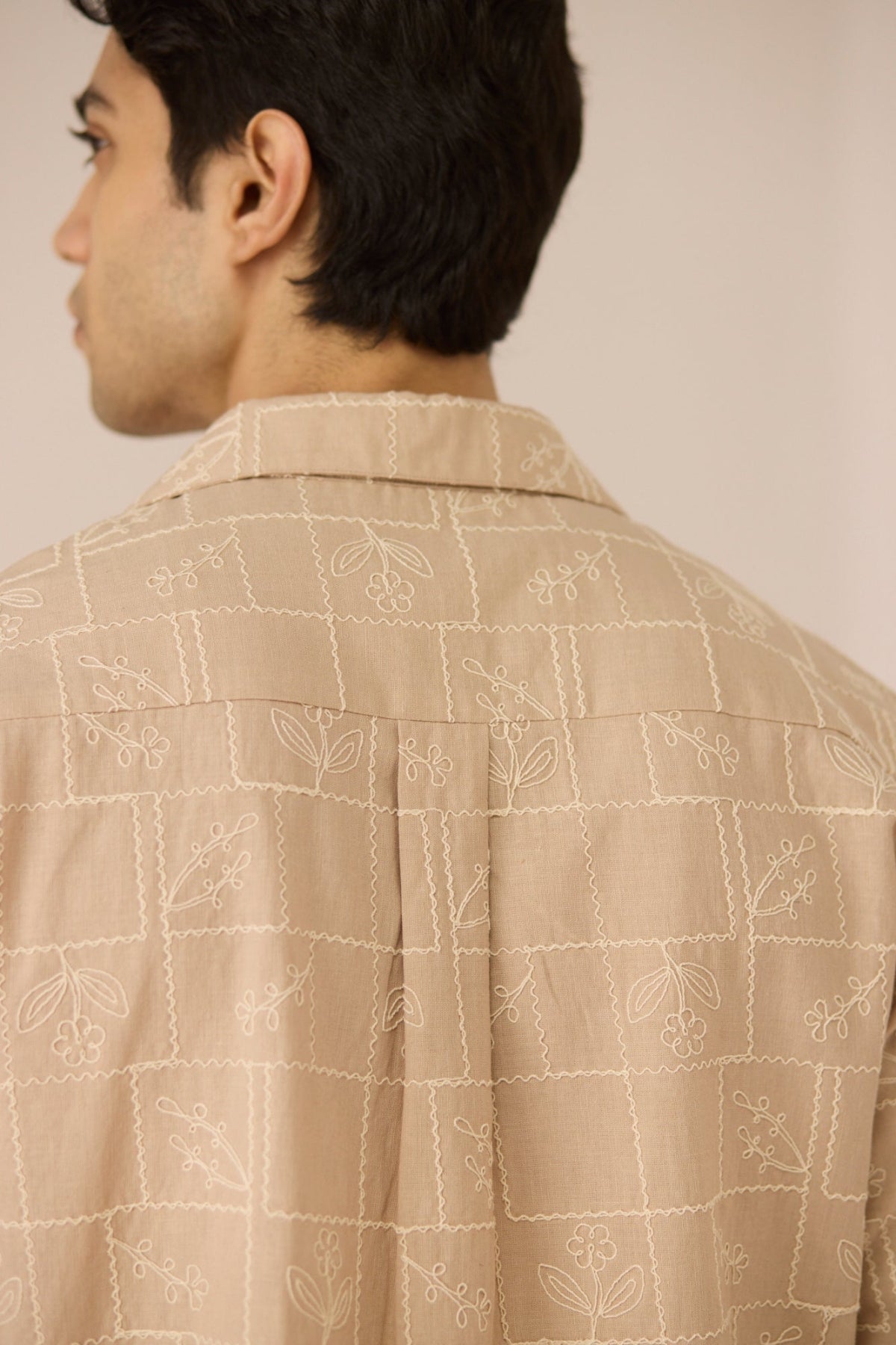 Man wearing a beige patterned shirt against a neutral background Calling June