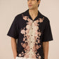 Man wearing a black floral shirt against a beige background Calling June