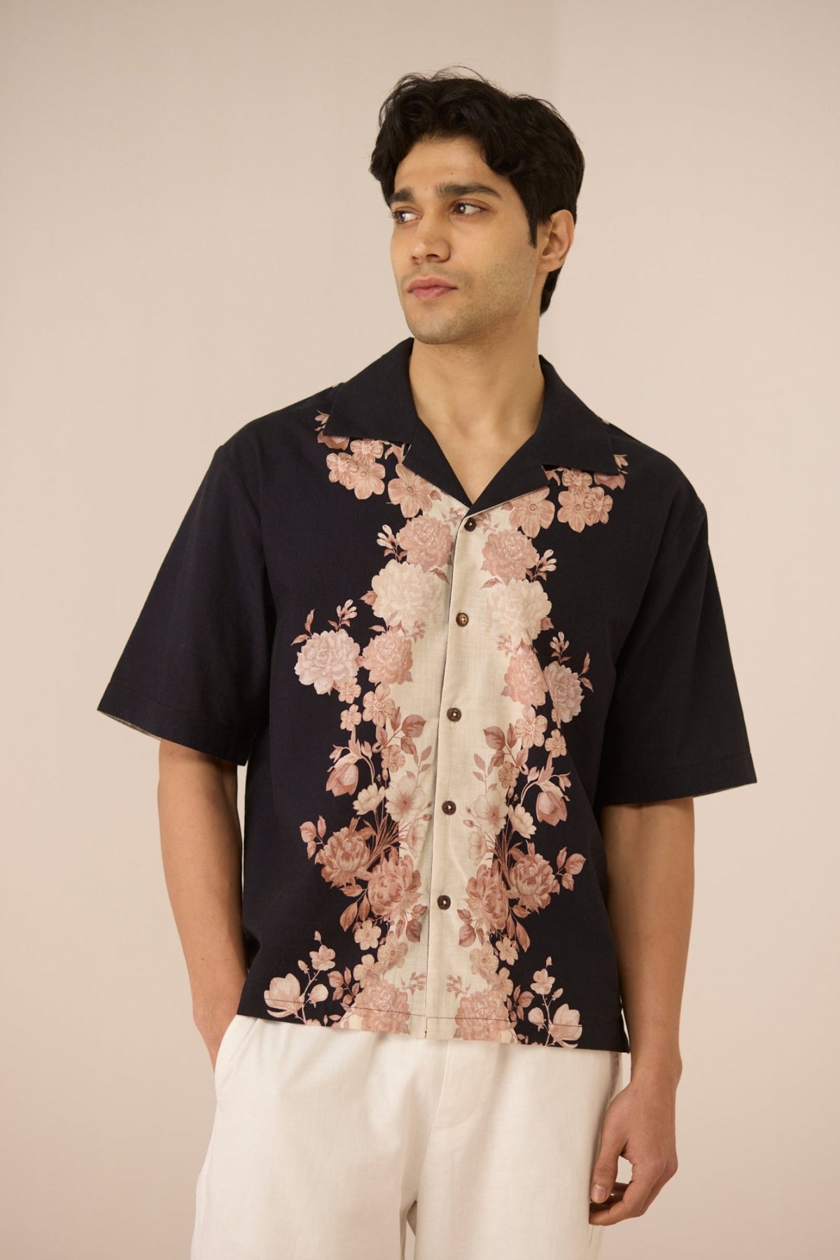 Man wearing a black floral shirt against a beige background Calling June