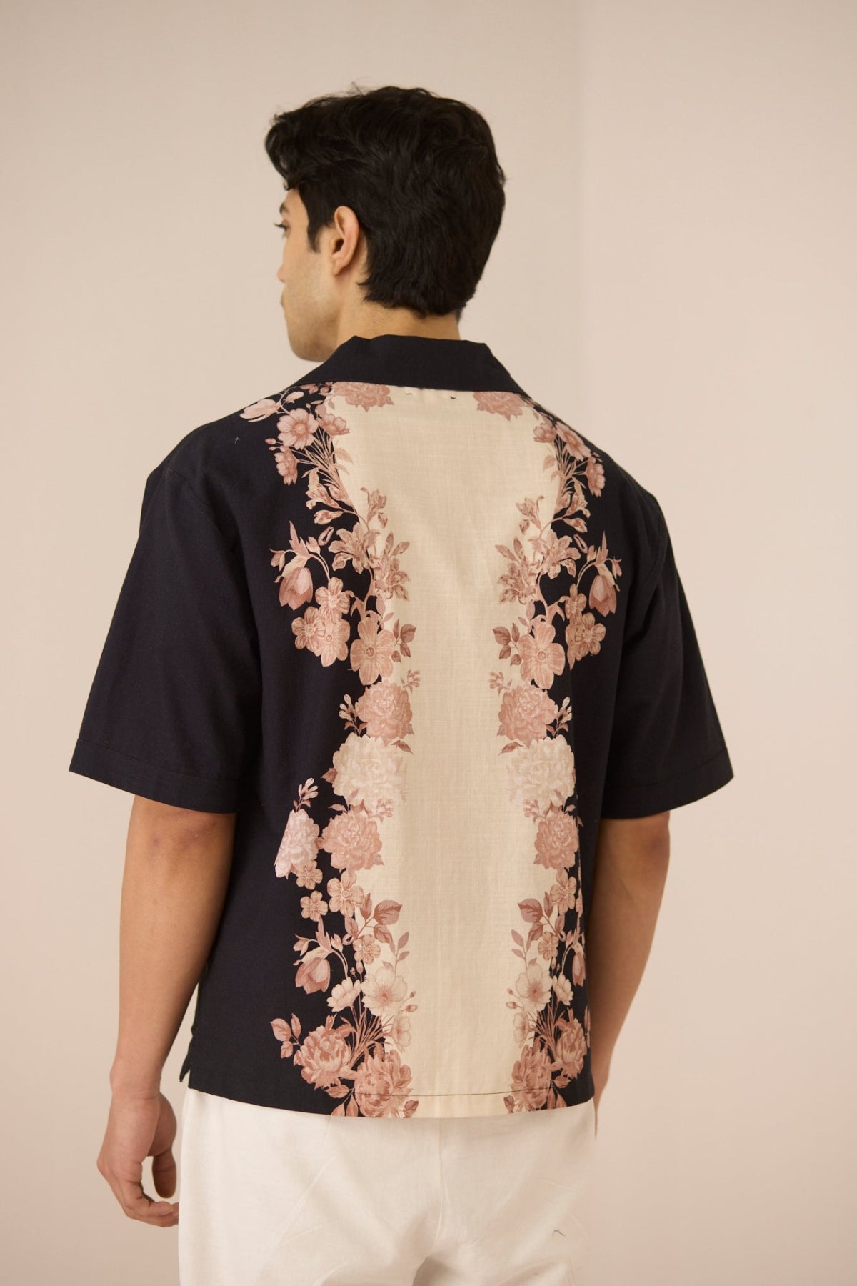Man wearing a black shirt with floral patterns on a beige background Calling June