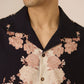 Man wearing a floral patterned shirt with a neutral background Calling June