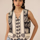 Woman wearing a sleeveless top with a black and white pattern against a beige background Calling June