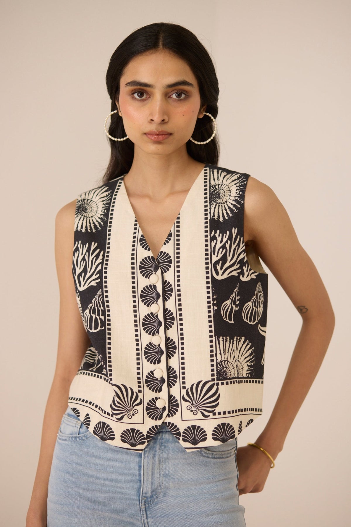 Woman wearing a sleeveless top with a black and white pattern against a beige background Calling June