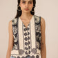 Woman wearing a sleeveless top with black and white pattern against a beige background Calling June