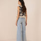 Woman wearing a floral top and light blue jeans on a beige background Calling June