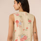 Woman wearing a floral embroidered sleeveless top against a beige background Calling June