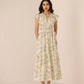 Woman wearing a floral dress against a plain background Calling June