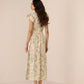 Woman wearing a floral dress against a plain background Calling June