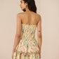 Woman wearing a strapless floral dress against a beige background Calling June