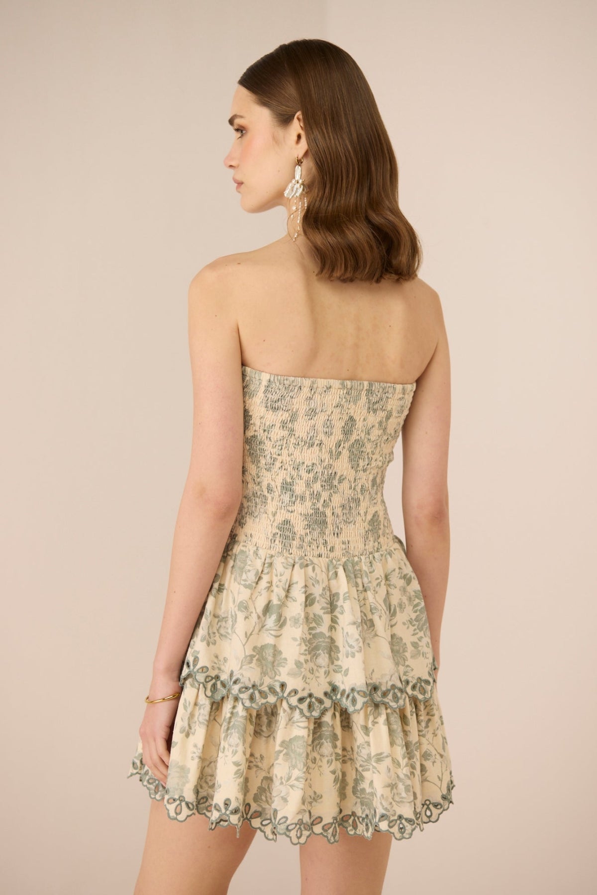 Woman wearing a floral strapless dress against a beige background Calling June