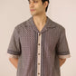 Man wearing a patterned shirt with a beige background Calling June