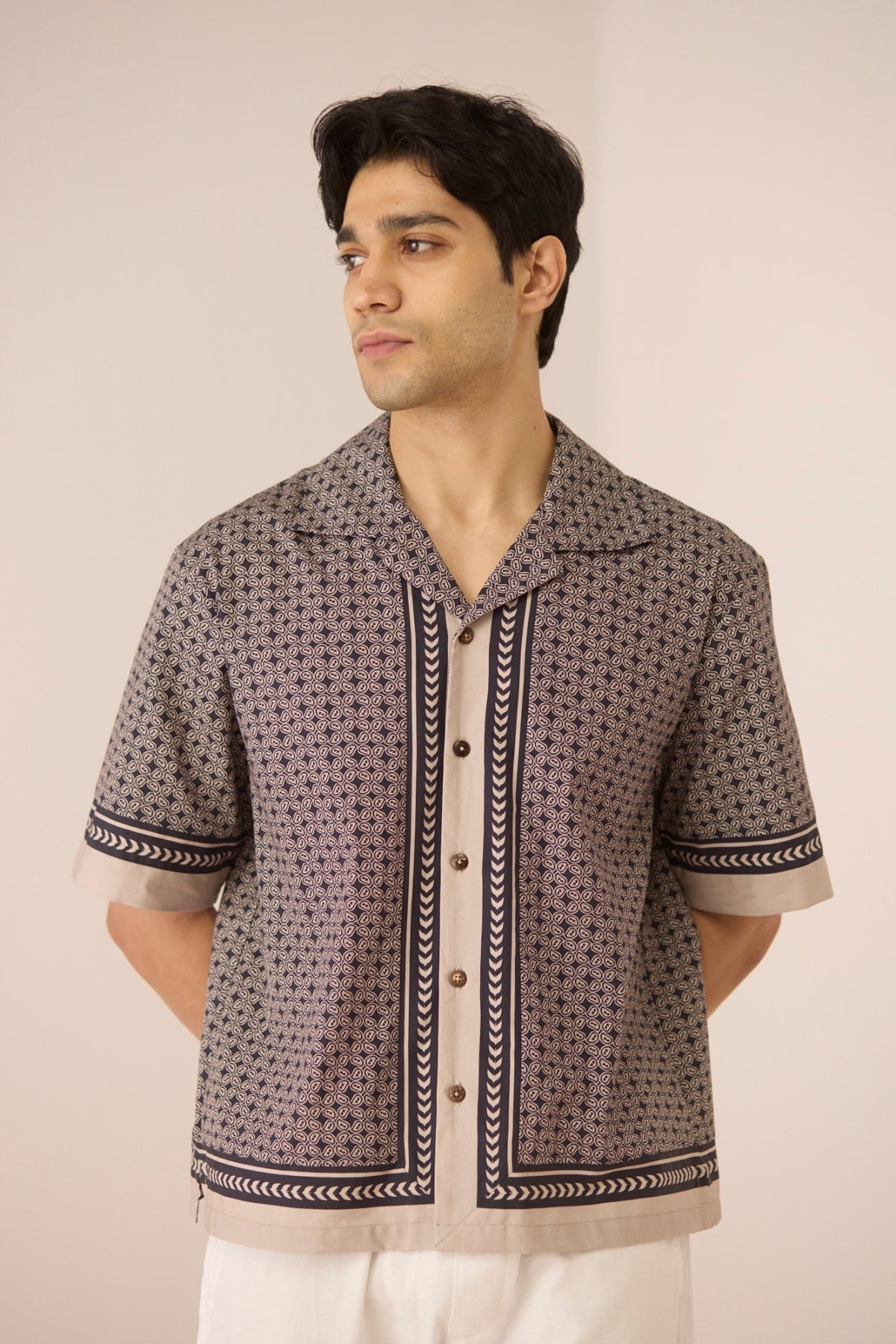 Man wearing a patterned shirt with a beige background Calling June