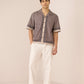 Man wearing a patterned short-sleeve shirt and white pants on a plain background Calling June