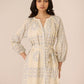 Woman wearing a beige patterned dress against a plain background Calling June