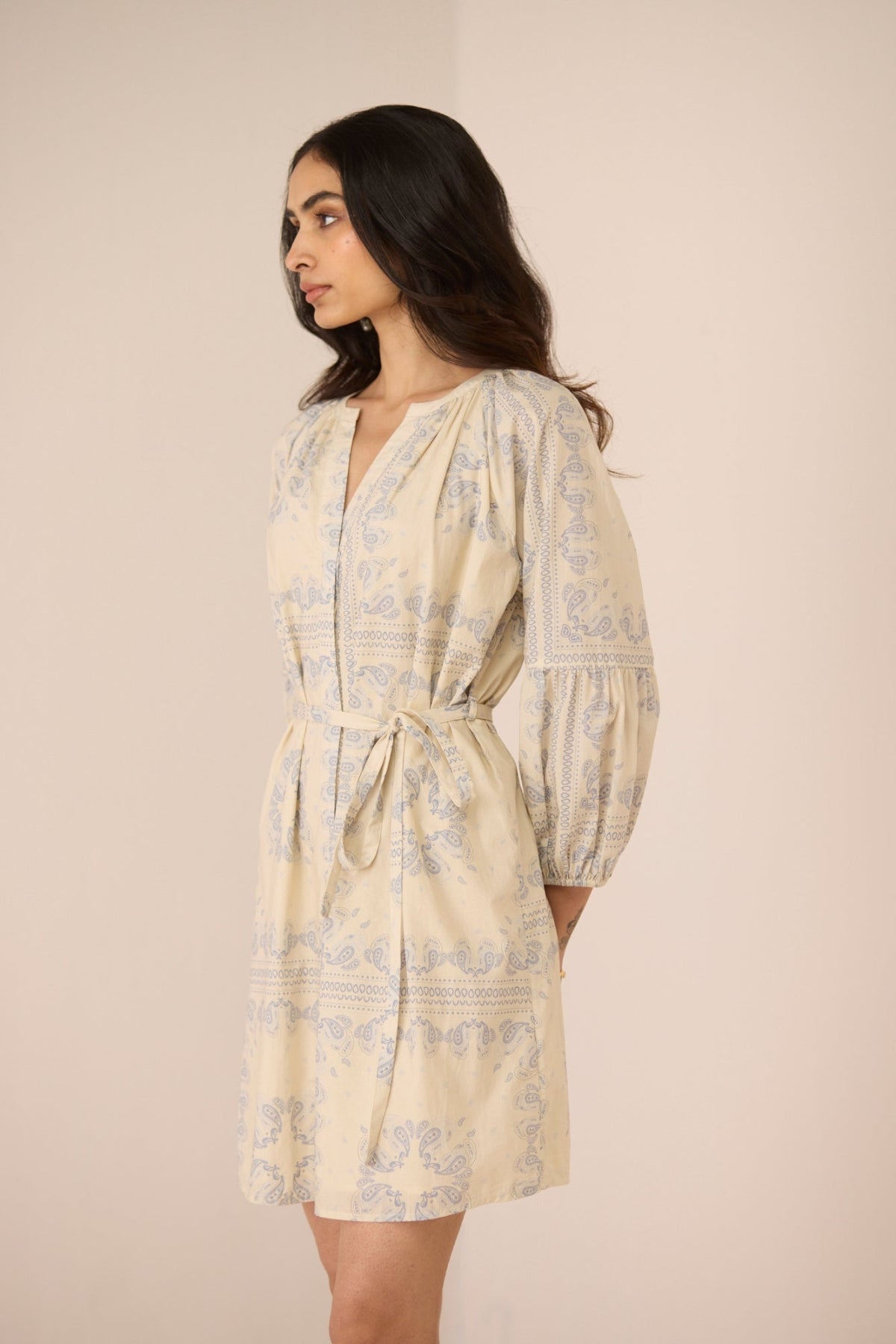 Woman wearing a light-colored dress with floral patterns against a beige background Calling June