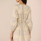 Woman wearing a beige floral dress against a beige background Calling June