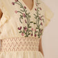 Cream-colored blouse with floral embroidery on a plain background Calling June