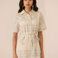 Woman wearing a beige dress with floral patterns against a plain background Calling June