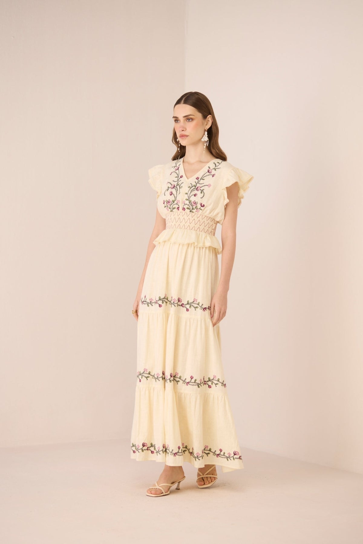 Woman wearing a light yellow set with floral embroidery on a beige background Calling June