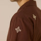 Brown shirt with floral embroidery on a plain background Calling June