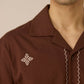 Close-up of a brown shirt with embroidery on a neutral background Calling June