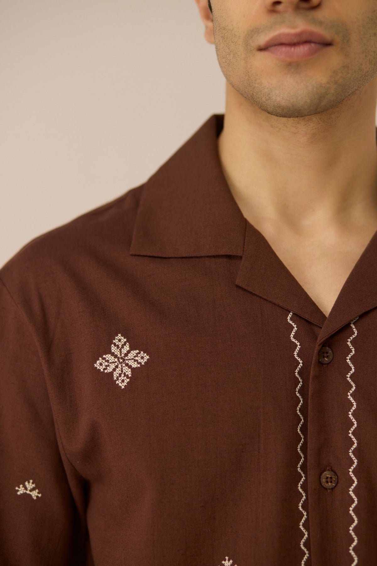 Close-up of a brown shirt with embroidery on a neutral background Calling June
