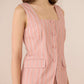 Woman wearing a pink striped sleeveless blazer over a matching dress against a beige background Calling June