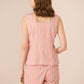 Woman wearing a pink striped sleeveless top and shorts set on a beige background Calling June
