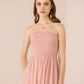 Woman wearing a pink strapless dress against a beige background Calling June