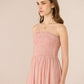 Woman wearing a pink strapless dress against a beige background Calling June