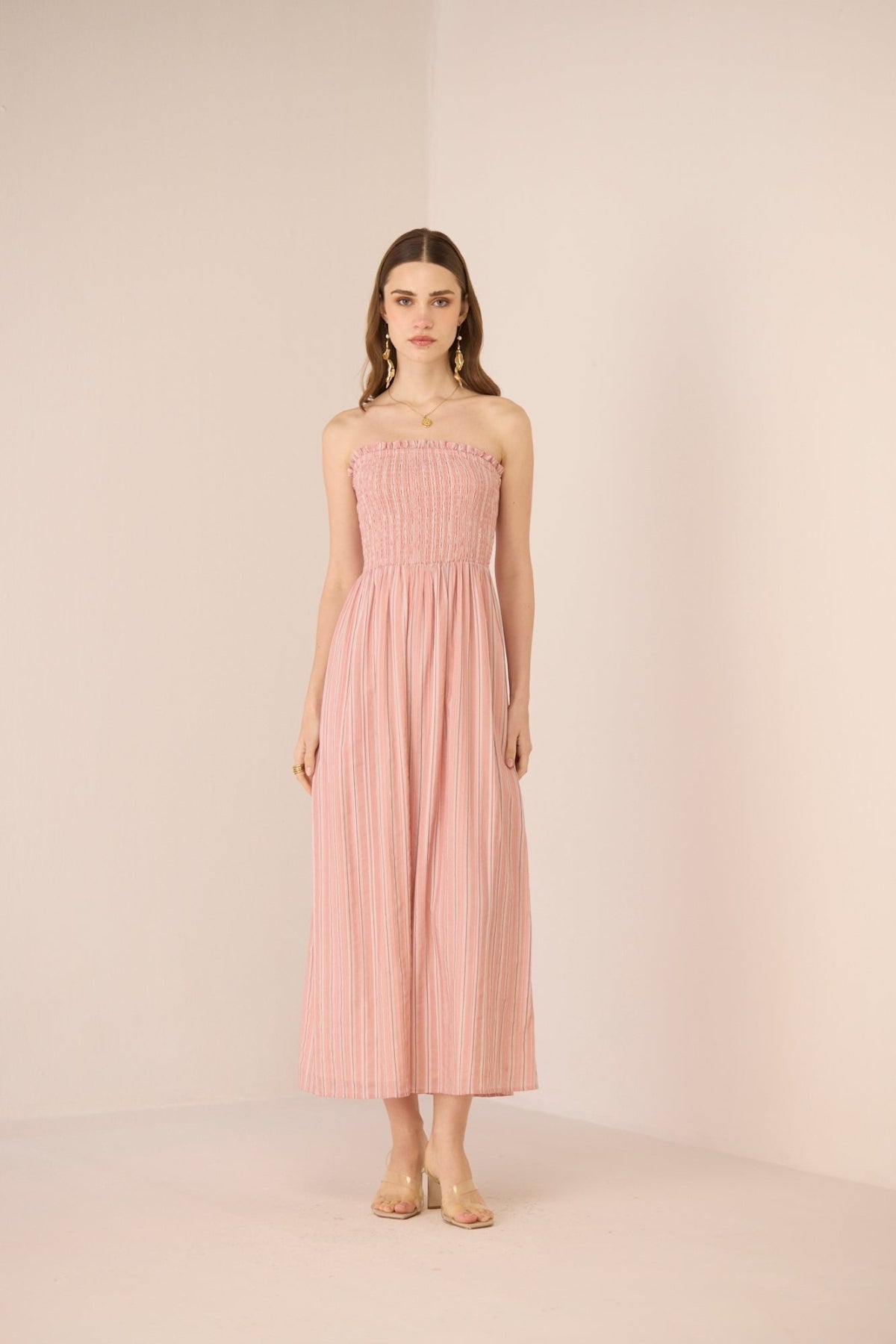 Woman wearing a pink strapless dress against a plain background Calling June