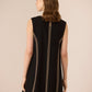 Black sleeveless dress with gold trim on a beige background Calling June