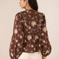 Woman wearing a brown floral blouse against a beige background Calling June