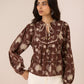 Woman wearing a brown floral blouse with a beige background Calling June