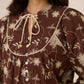 Woman wearing a brown floral dress with a close-up of the neckline Calling June