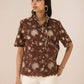 Woman wearing a brown floral blouse against a beige background Calling June