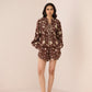 Woman wearing a brown floral dress against a plain background Calling June