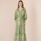 Woman wearing a green embroidered dress against a beige background Calling June