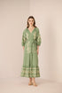 Woman wearing a green embroidered dress against a beige background Calling June