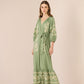 Woman wearing a green embroidered dress on a beige background Calling June