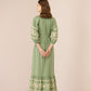 Woman wearing a green dress with floral embroidery on a beige background Calling June