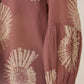 Brown blouse with beige floral patterns worn by a person, on a neutral background Calling June