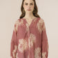 Woman wearing a patterned blouse with a plain background Calling June