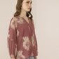 Woman wearing a patterned blouse with a plain background Calling June
