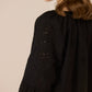 Black dress with intricate cut-out patterns on a beige background Calling June