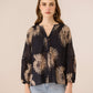 Woman wearing a black blouse with gold floral patterns on a beige background Calling June