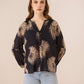 Woman wearing a black blouse with beige floral patterns on a beige background Calling June